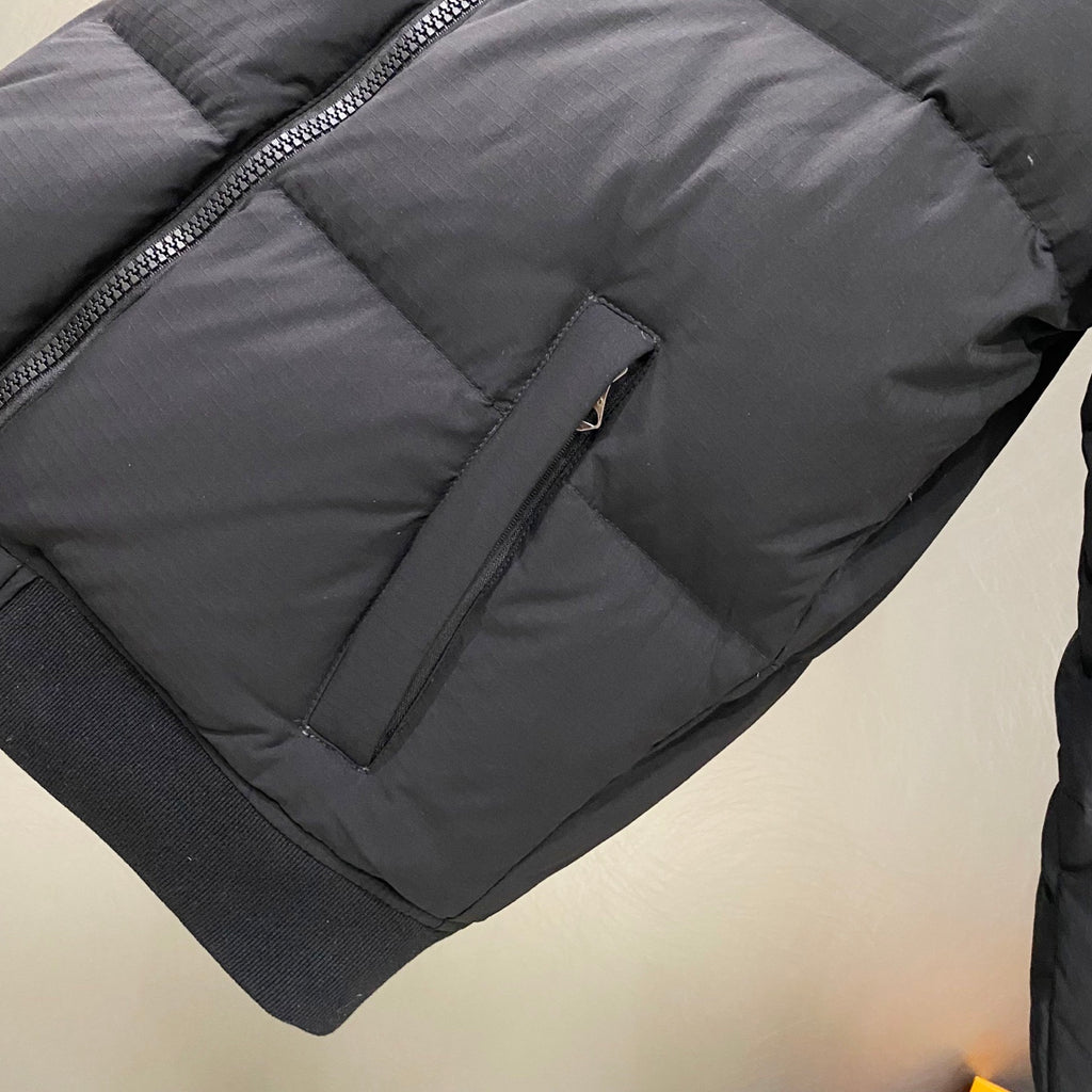 Dark puffer jacket sleeve with zipper pocket detail