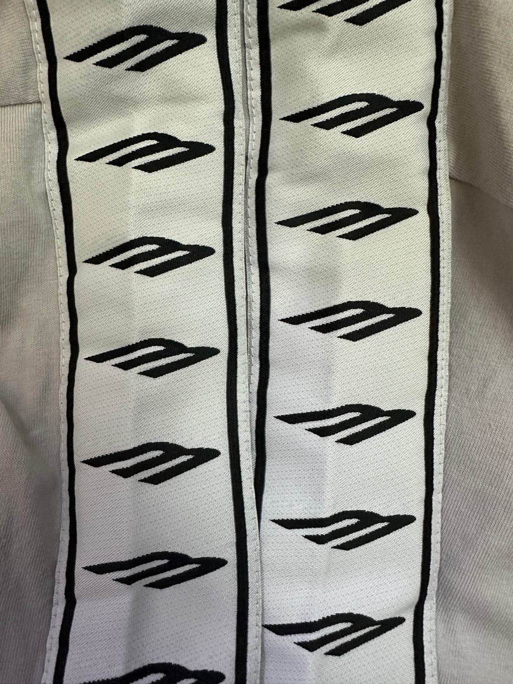 Black logo pattern trim on white T-shirt sleeve edge, vertical decorative strip