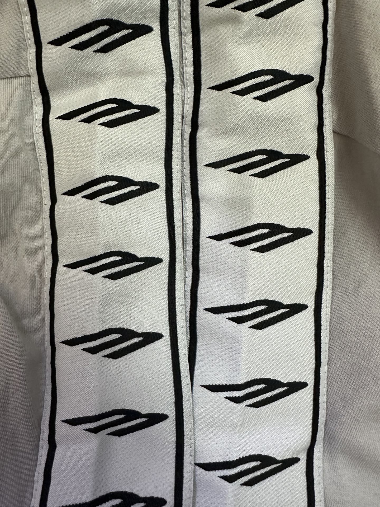 Black logo pattern trim on white T-shirt sleeve edge, vertical decorative strip