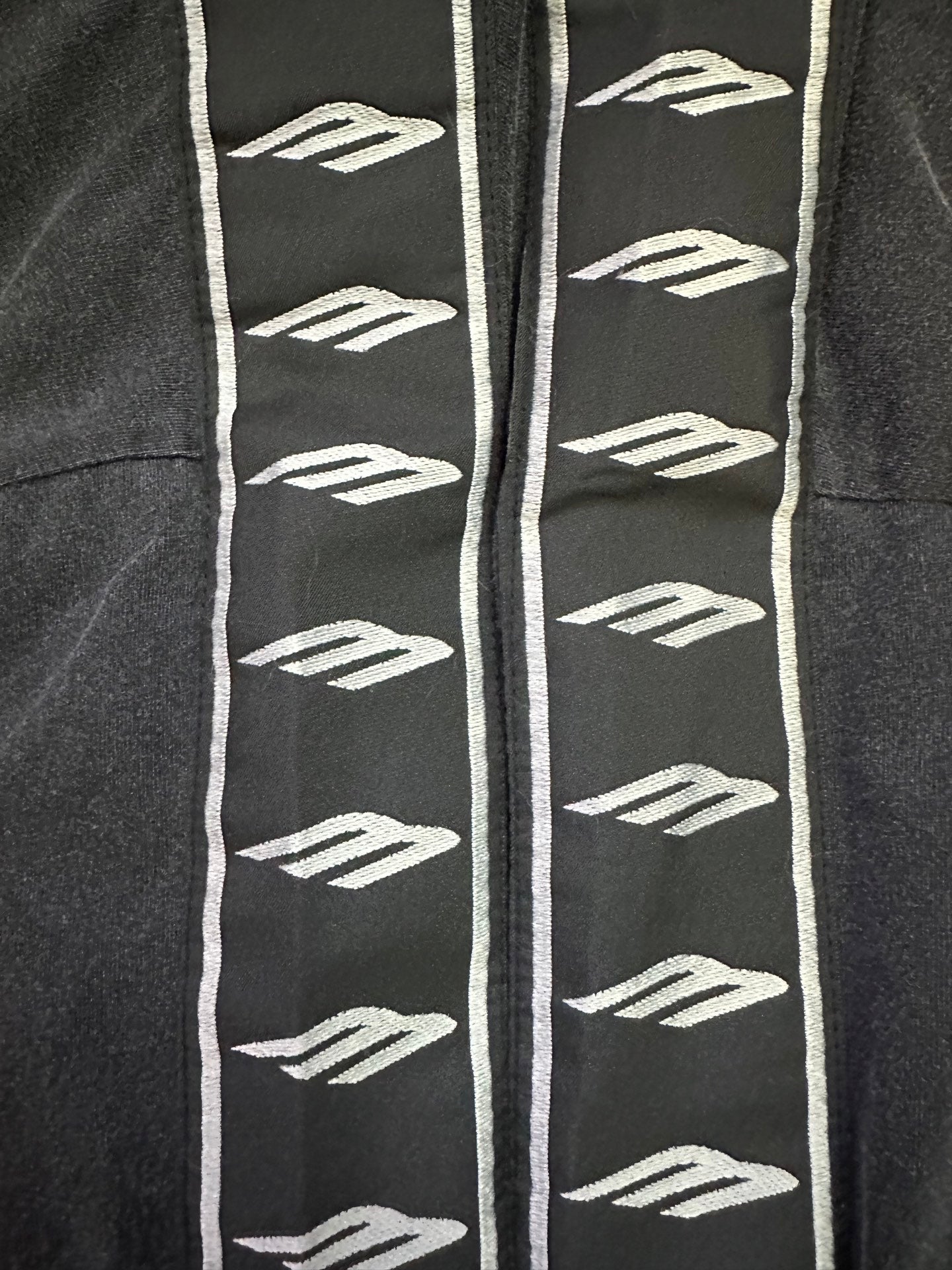Black T-shirt sleeve with repeating white logo graphics and white trim