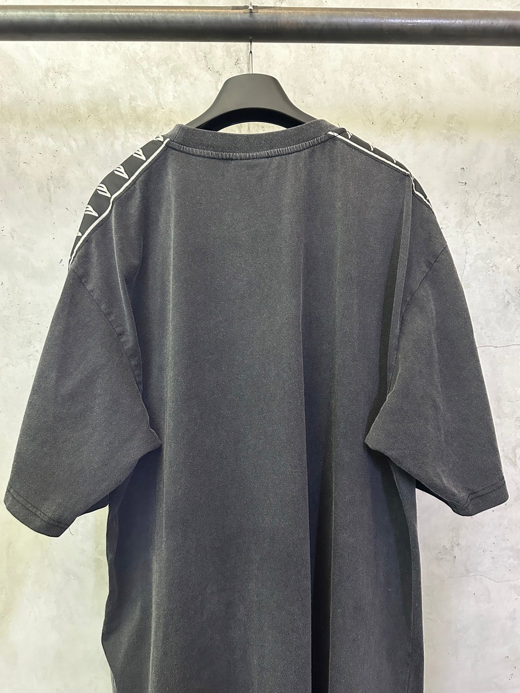 Men's black crew-neck T-shirt, back view with white logo tape on shoulders
