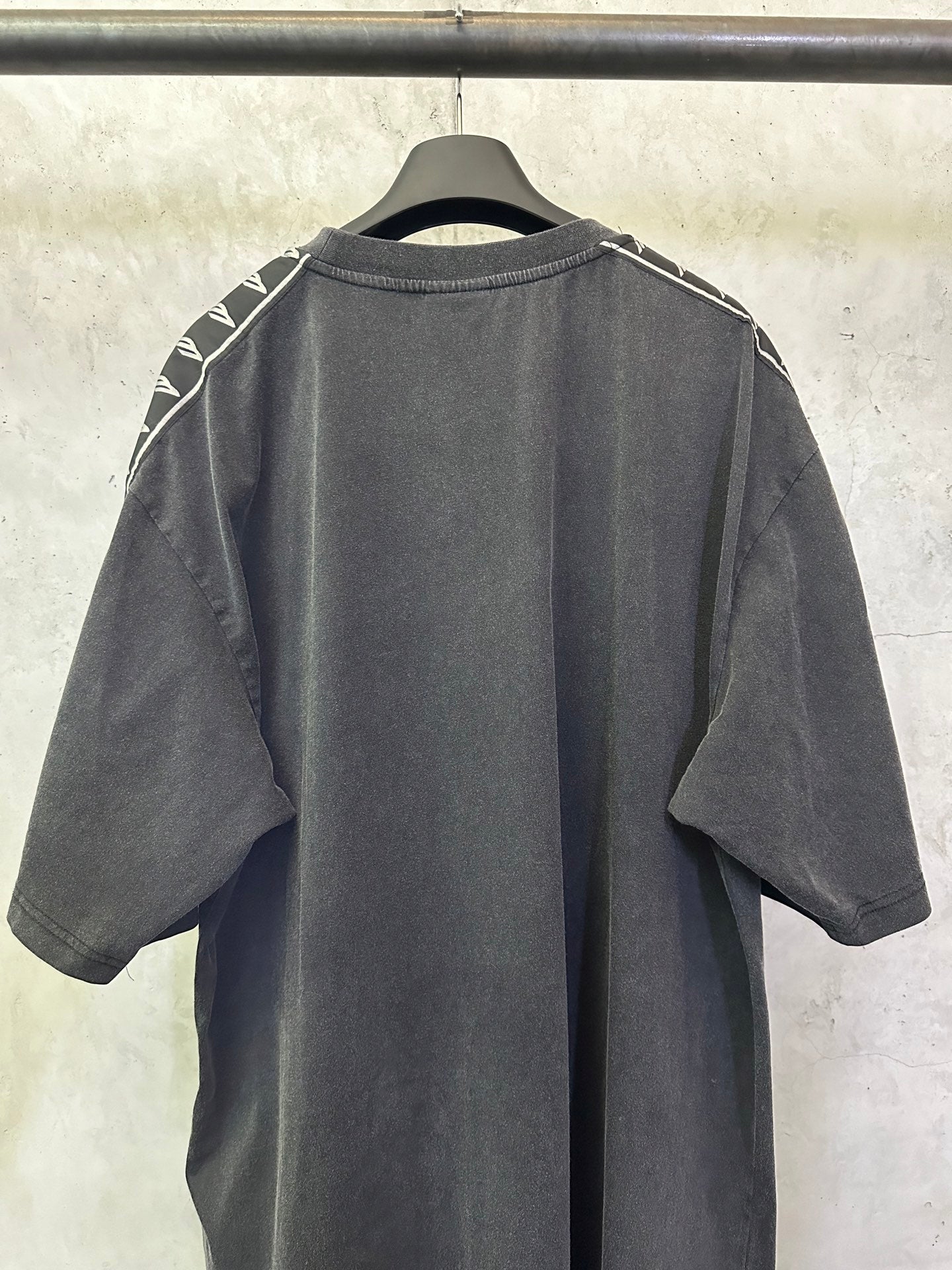 Men's black crew-neck T-shirt, back view with white logo tape on shoulders