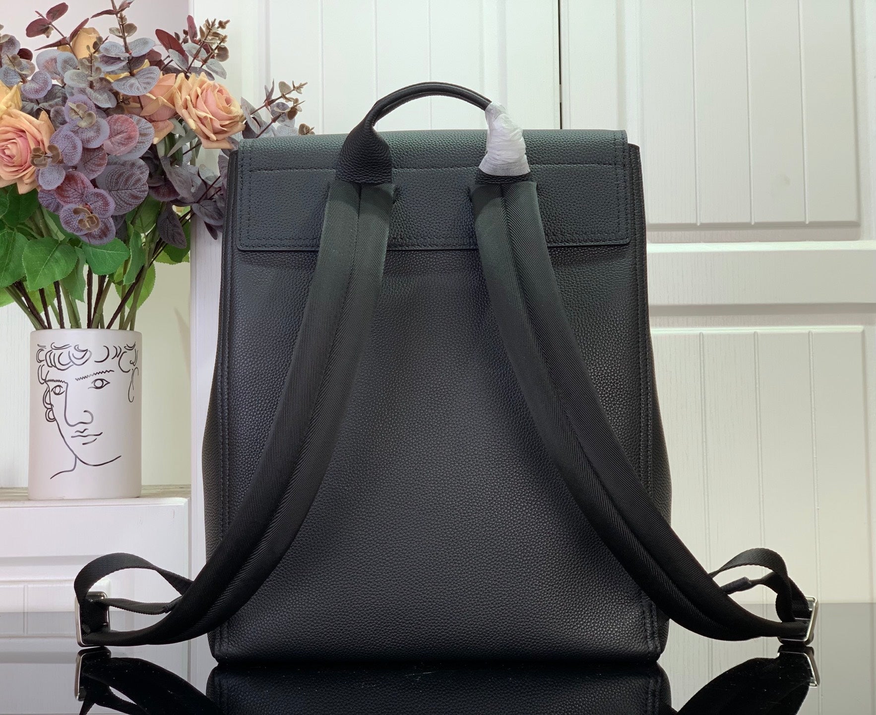 Louis Vuitton backpack with flap top and two adjustable shoulder straps, dark textured leather