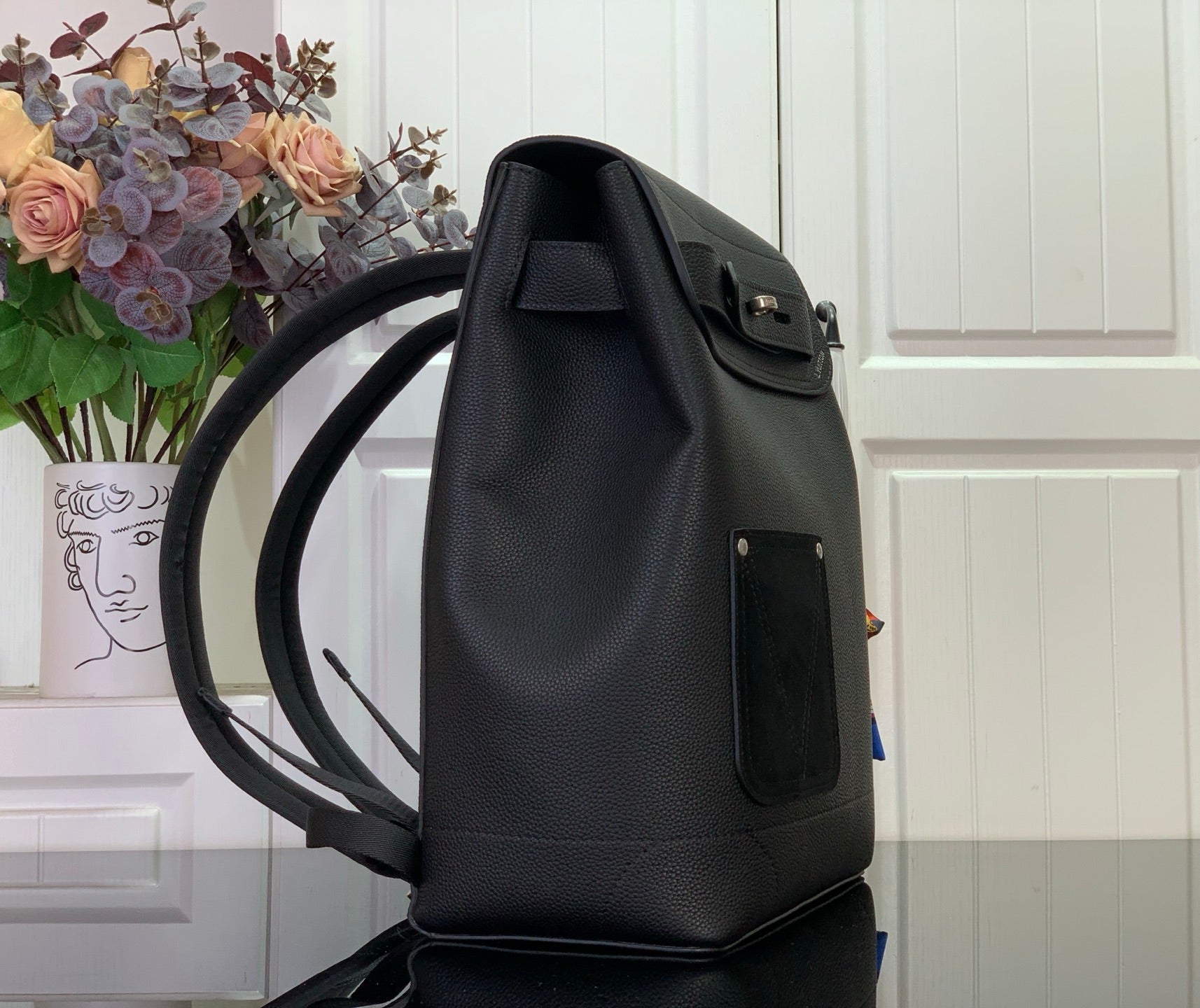 Louis Vuitton backpack angled view with front flap, side pocket, and adjustable shoulder straps