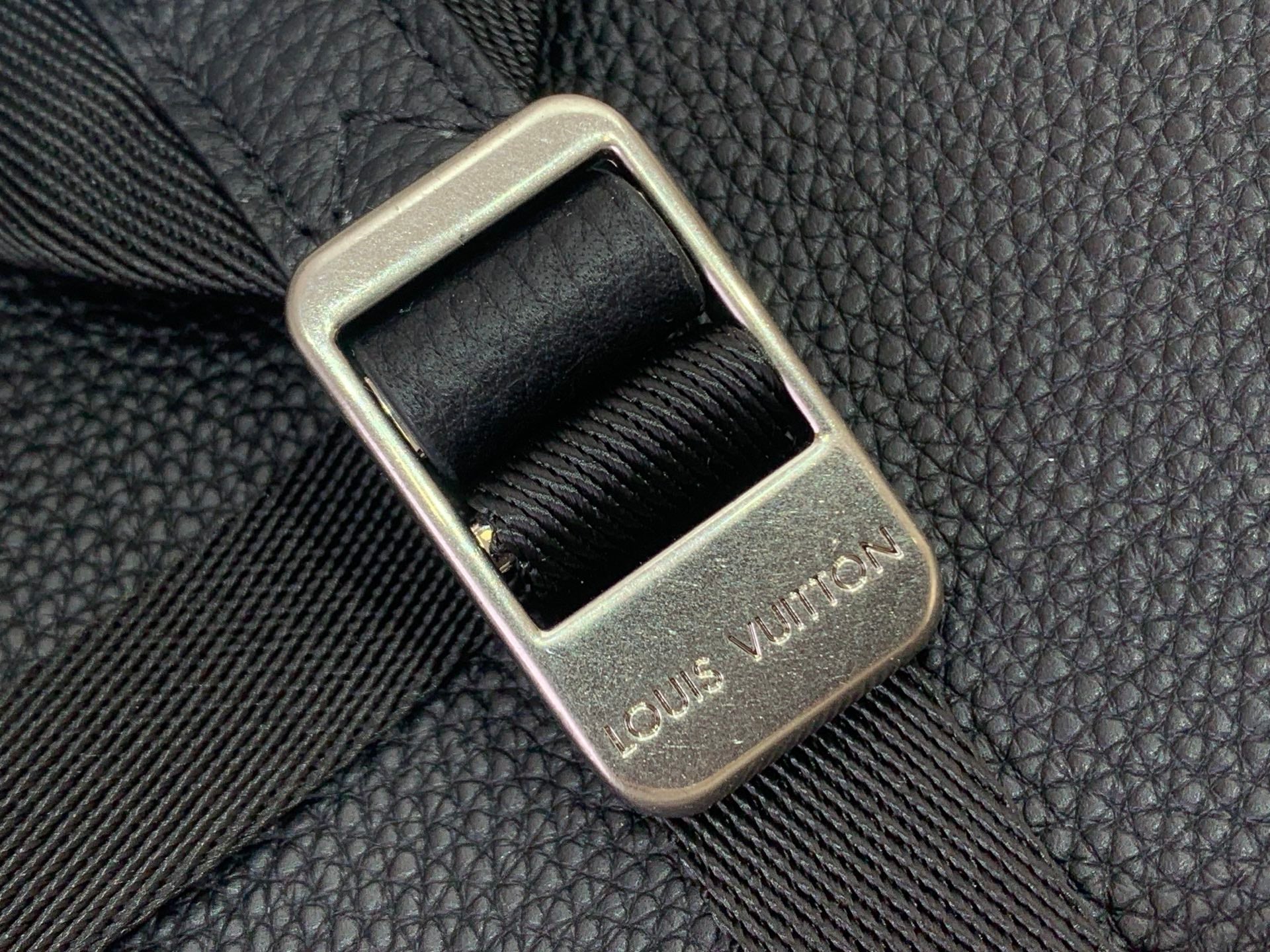 Louis Vuitton backpack close-up of gold-toned buckle on textured leather strap