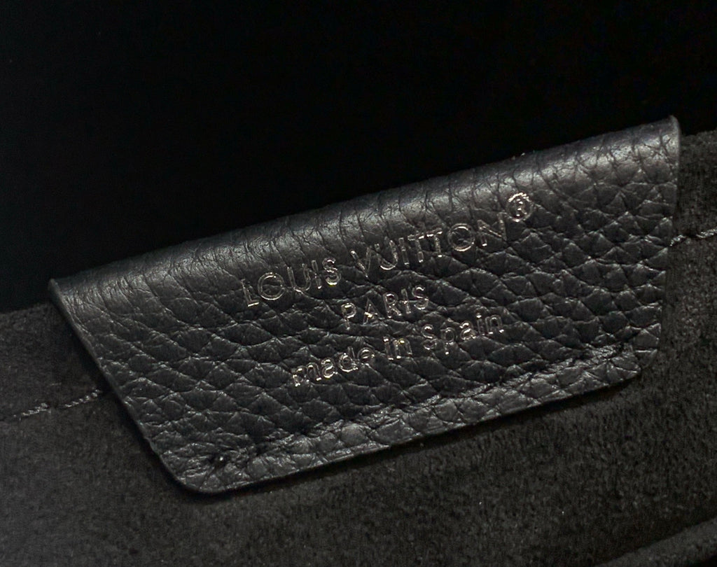Louis Vuitton leather backpack close-up of embossed brand logo on flap