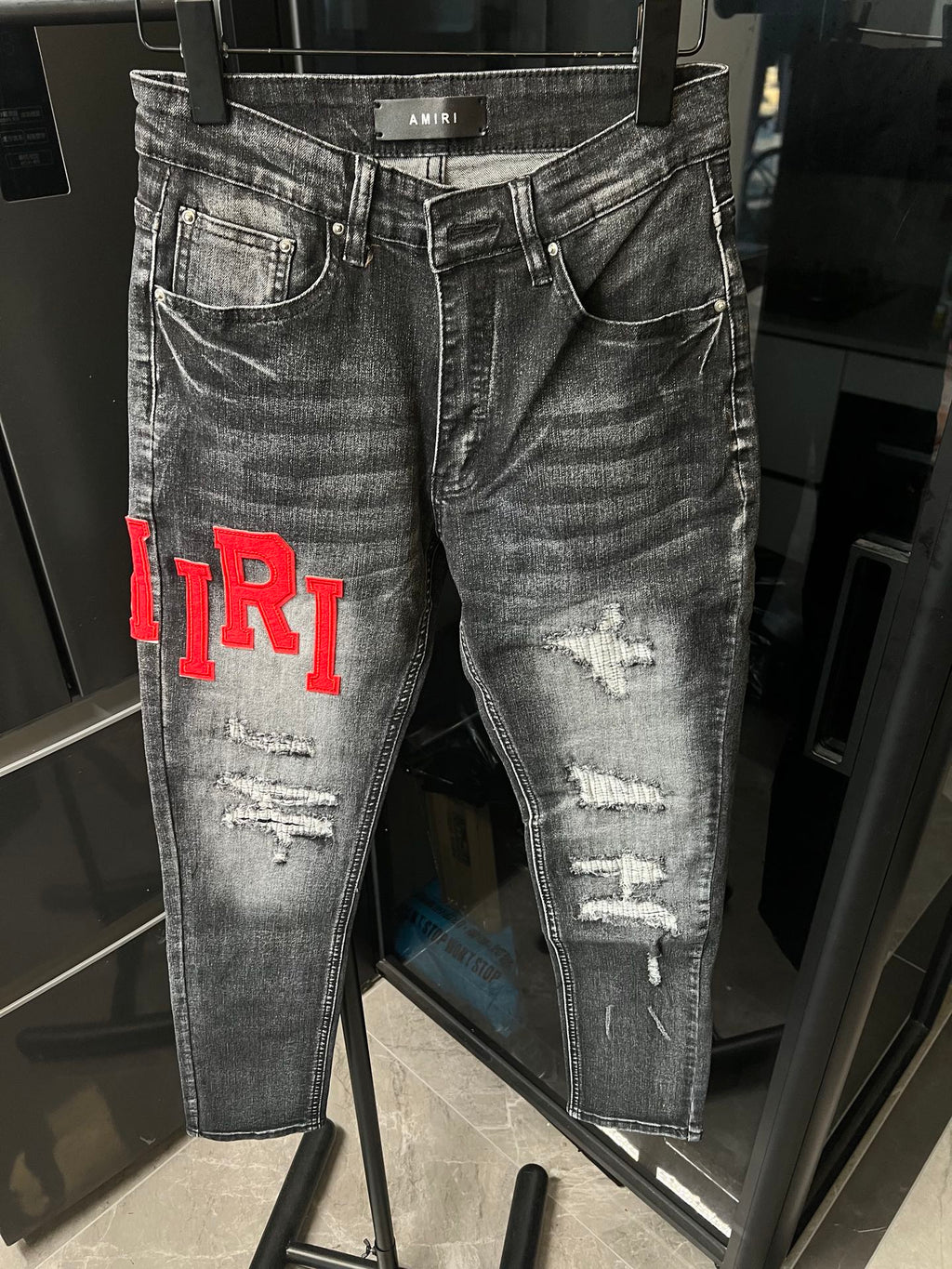 Gray distressed denim jeans with waistband label and red 'TR1' on the side
