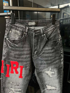 Gray distressed denim jeans with red 'TR1' detail on the left leg