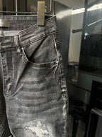 Gray denim jeans close-up with distressed patches and buttoned front waistband