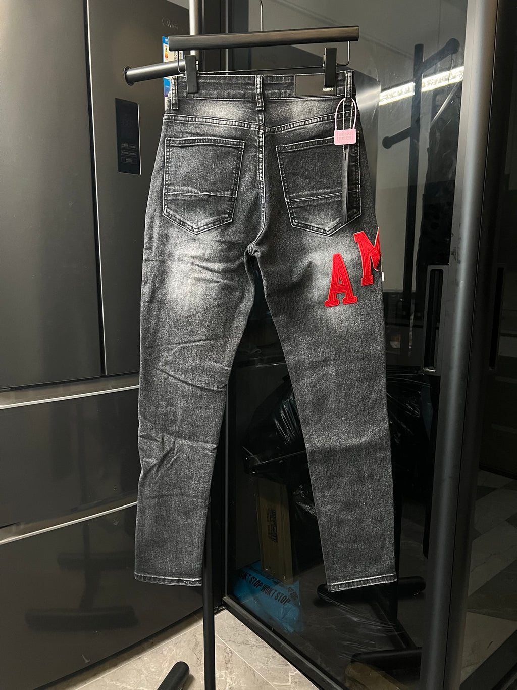 Gray distressed denim jeans with red 'AM' lettering on the right leg
