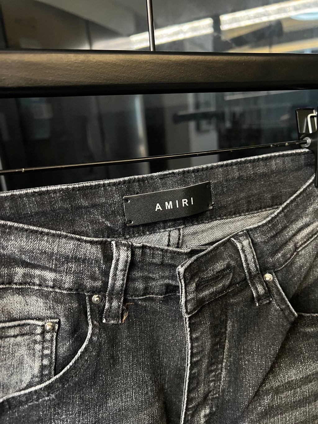 Gray denim jeans close-up with waistband patch and front belt loops