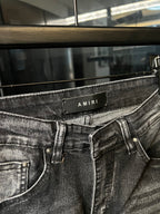 Gray denim jeans close-up with waistband patch and front belt loops