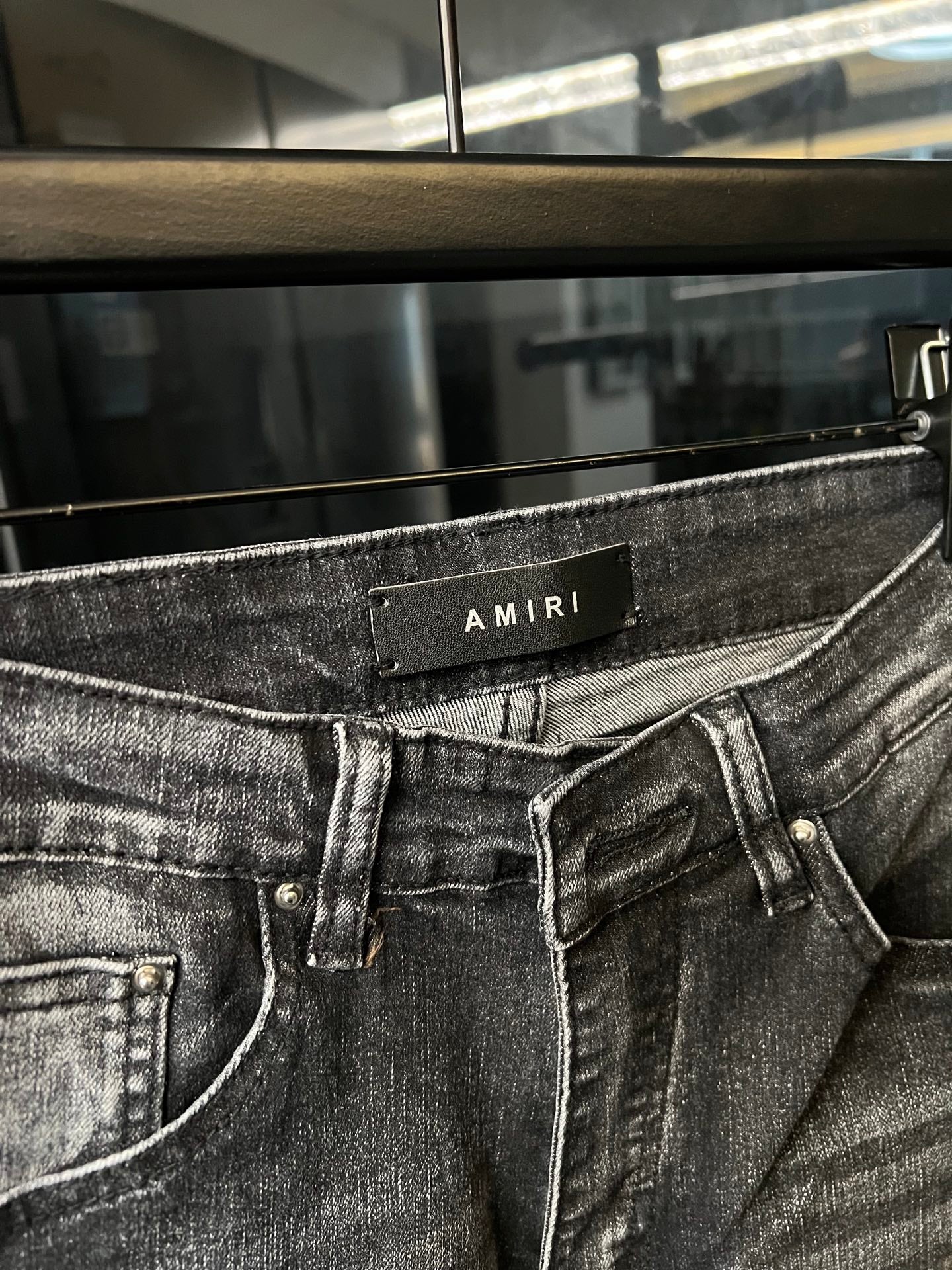 Gray denim jeans close-up with waistband patch and front belt loops