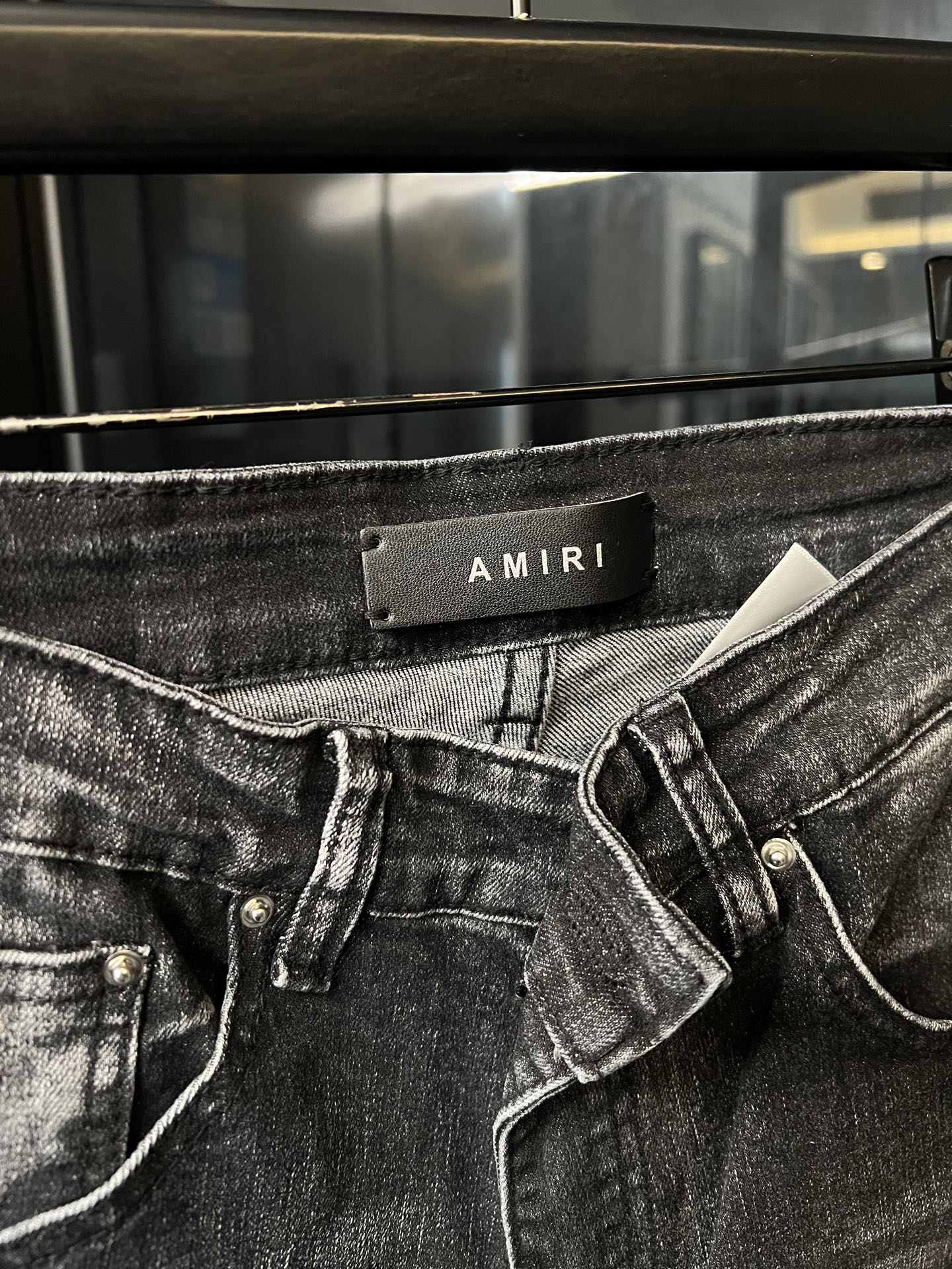 AMIRI waist label on dark denim jeans with button-fly and belt loops