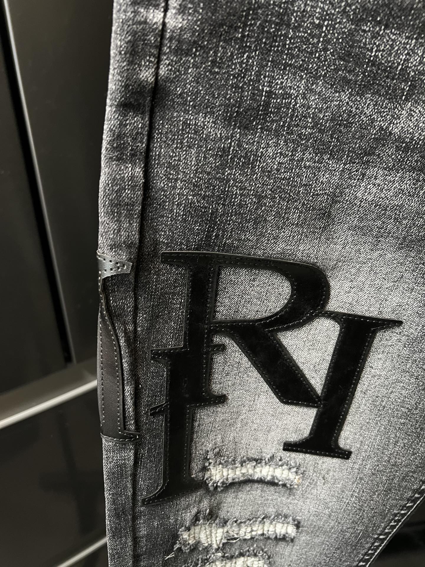 R monogram on distressed dark denim jeans, ripped front knee and thigh