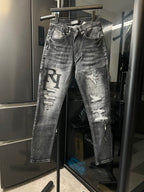 Distressed light-gray denim jeans with ripped knees and large black R applique