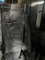 Light-gray denim jeans close-up with front pocket and AM logo print