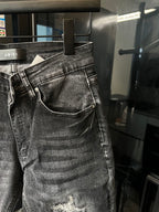 Front close-up of AMIRI dark denim jeans, pocket seams and distressed knee
