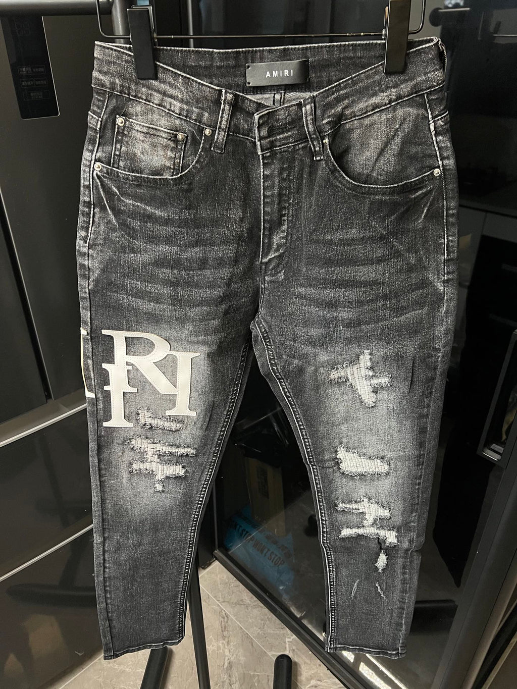 Light-wash distressed denim jeans with big RI logo patch on left leg