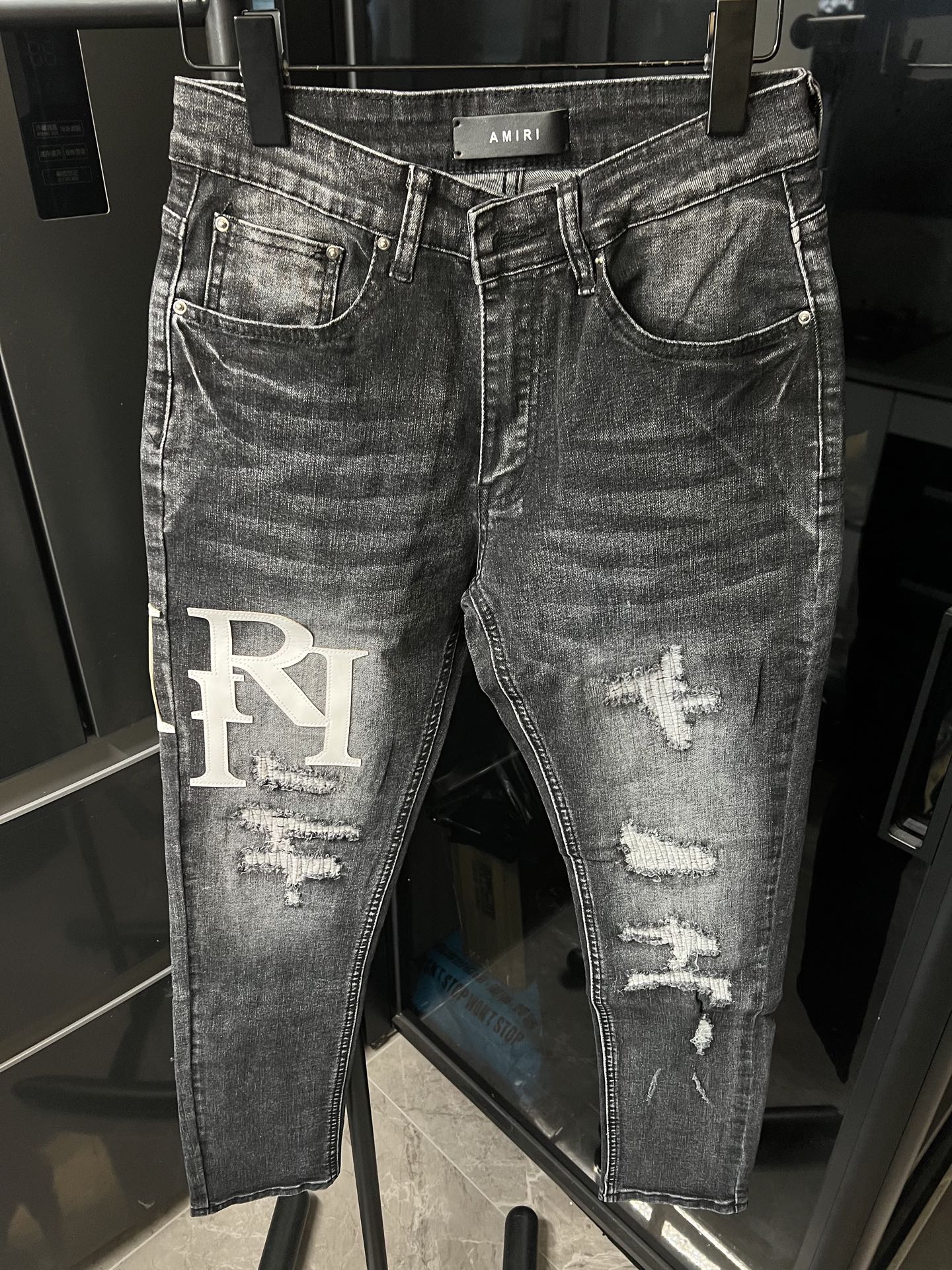 Light-wash distressed denim jeans with big RI logo patch on left leg