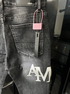Light-wash denim jeans with AM logo print and pink tag hanging at waistband
