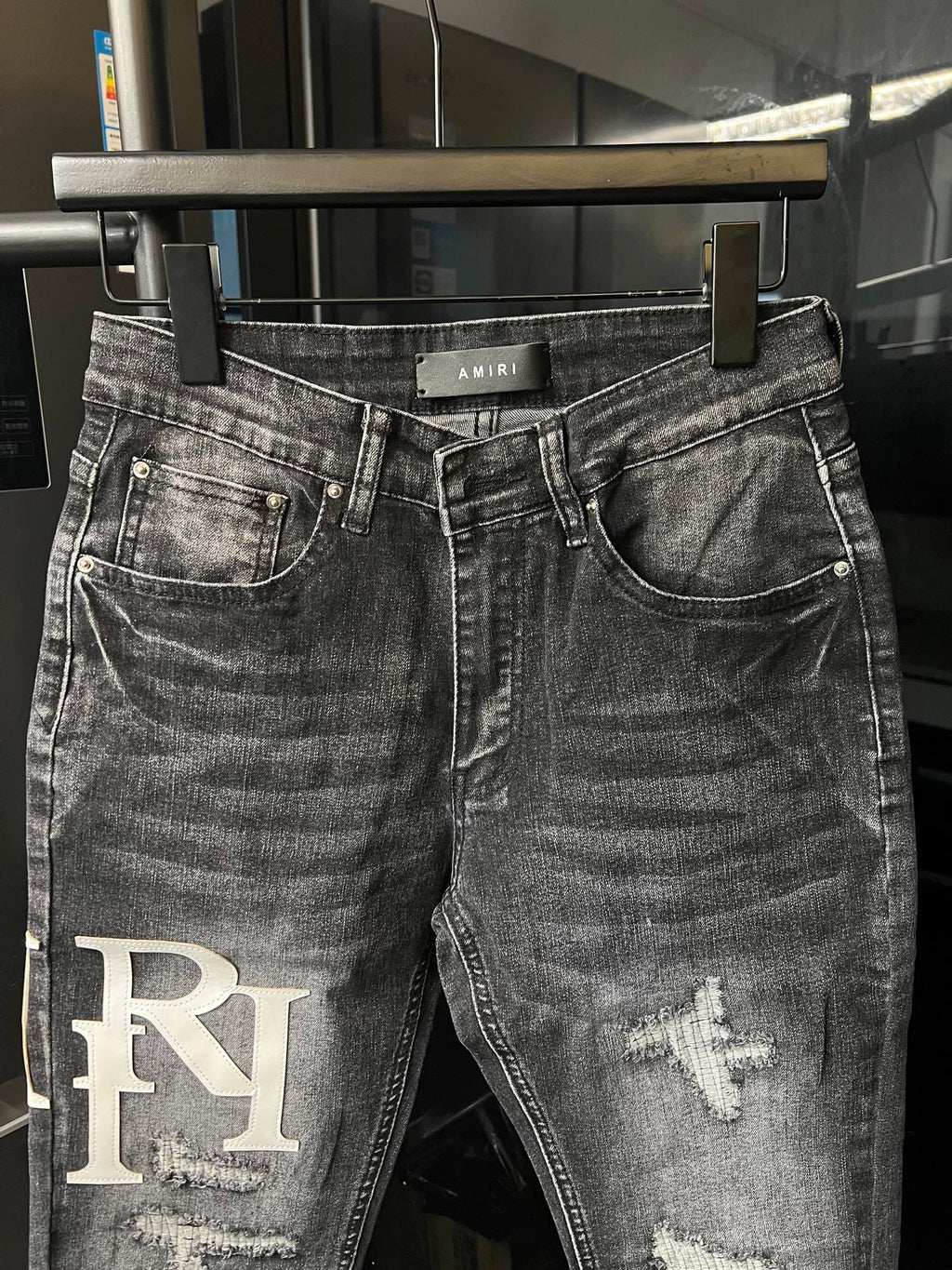 Light-wash denim jeans with AMIRI waistband label and RI patch at left leg