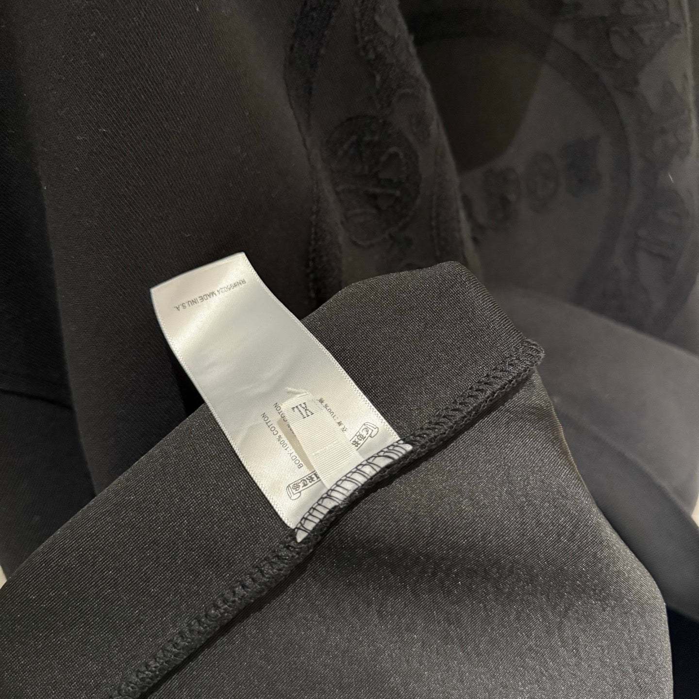 Black hoodie care label on sleeve cuff with embroidered logo detail