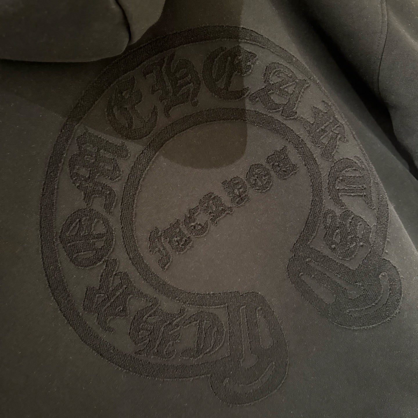 Black embroidered oval face logo on hoodie front