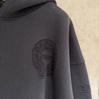 Black hoodie close-up with oval face applique and distressed sleeve graphic