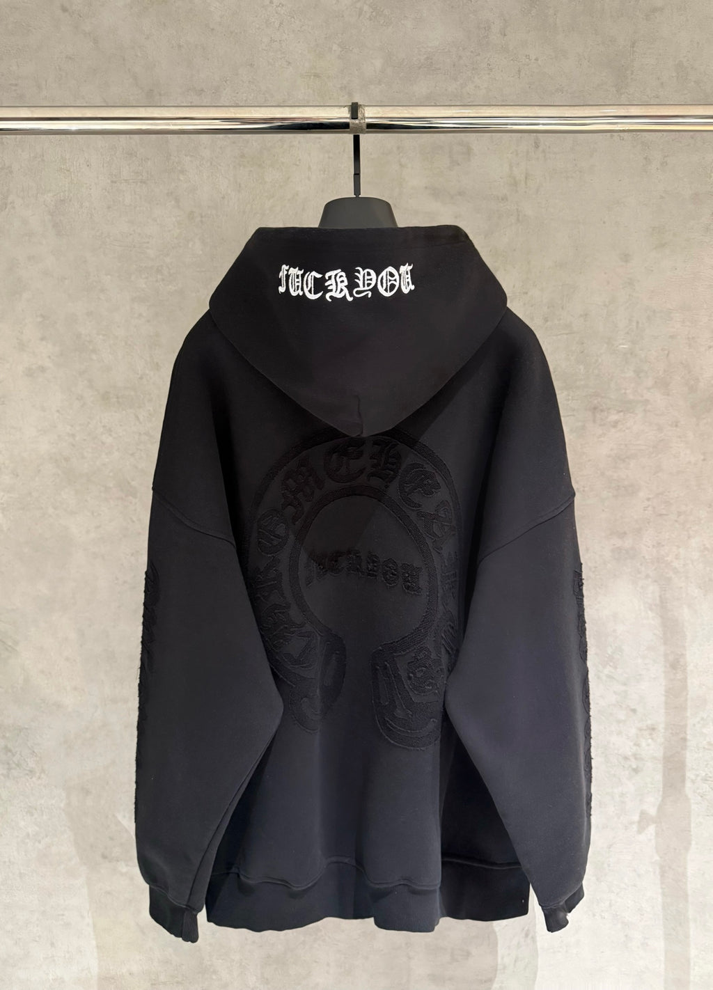 Black hoodie back view with hood, white text graphic, and large oval logo on chest
