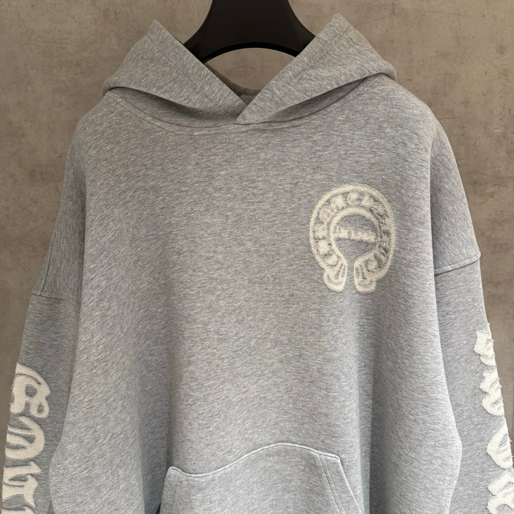 Gray hoodie with hood and small chest emblem, front view.