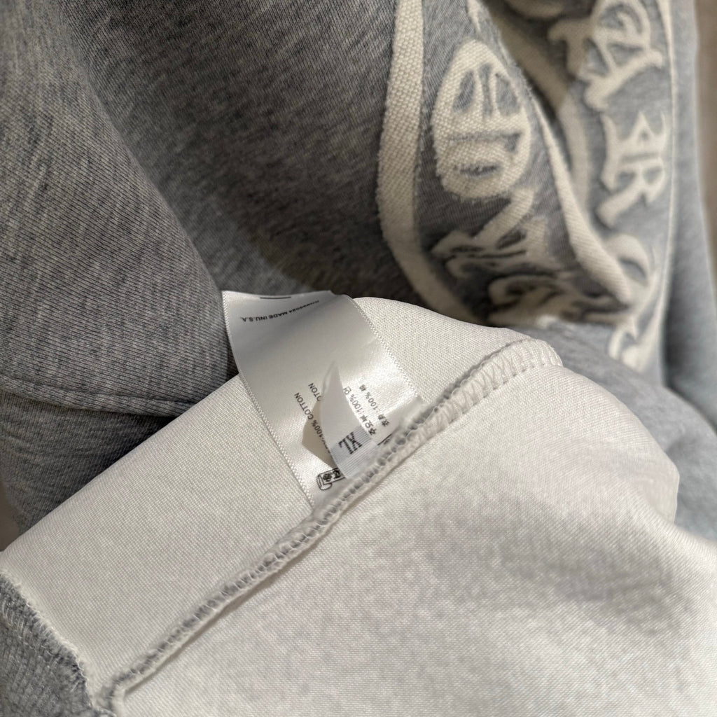Gray hoodie fabric close-up with inner label near the sleeve cuff.
