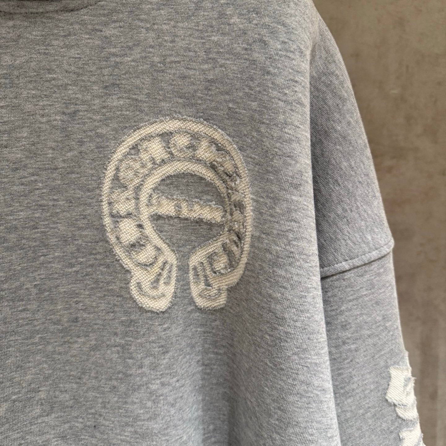 Gray hoodie sleeve with large circular emblem print.
