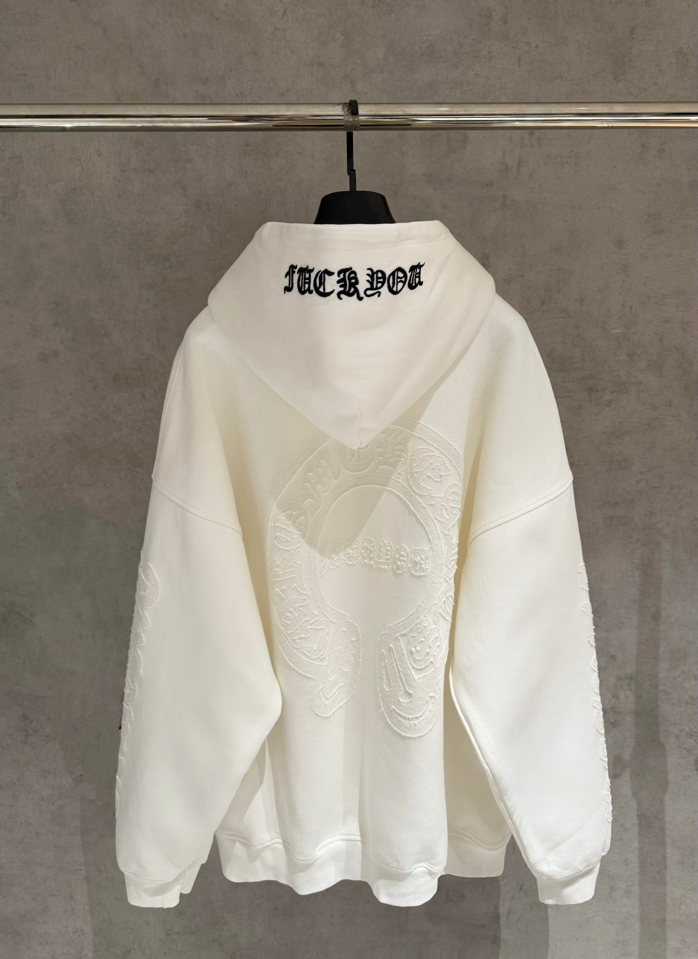 Off-white hoodie back view with hood, embroidered text across upper back and face graphic