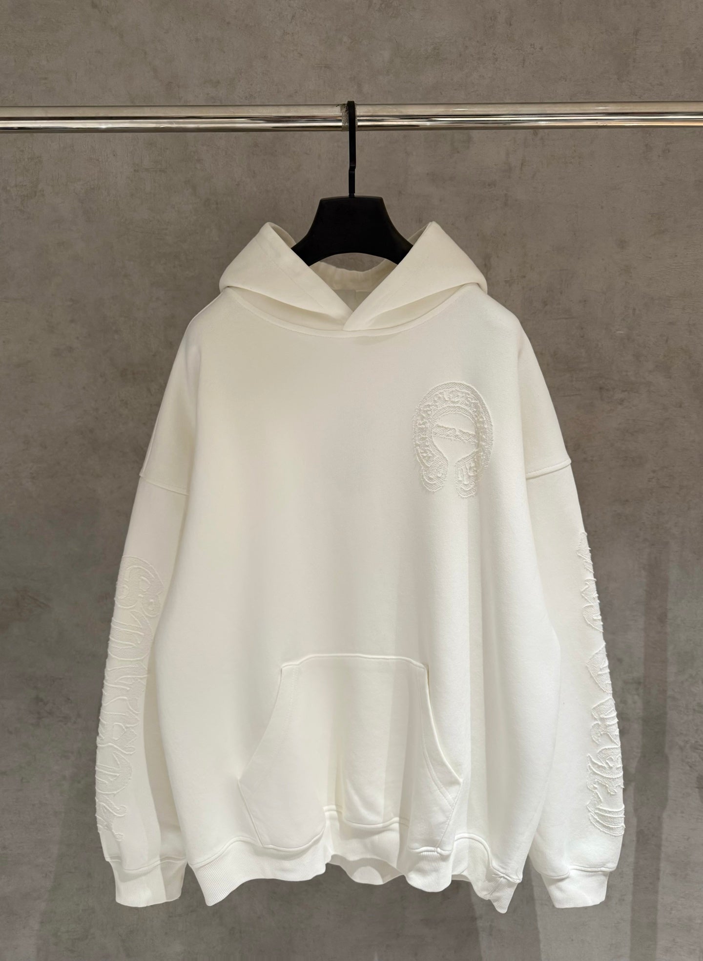Off-white long-sleeve hoodie with hood and kangaroo pocket, embossed face chest logo