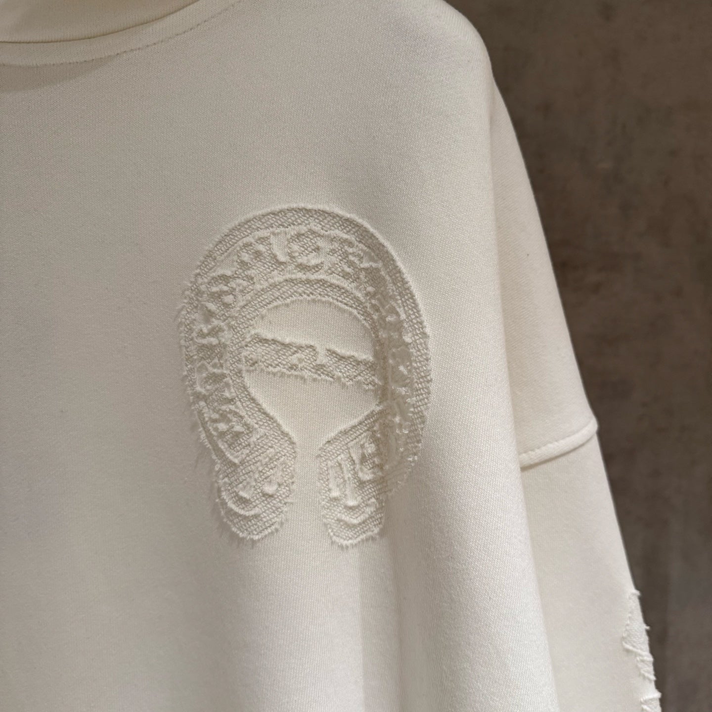 Off-white hoodie sleeve area with embossed face logo print