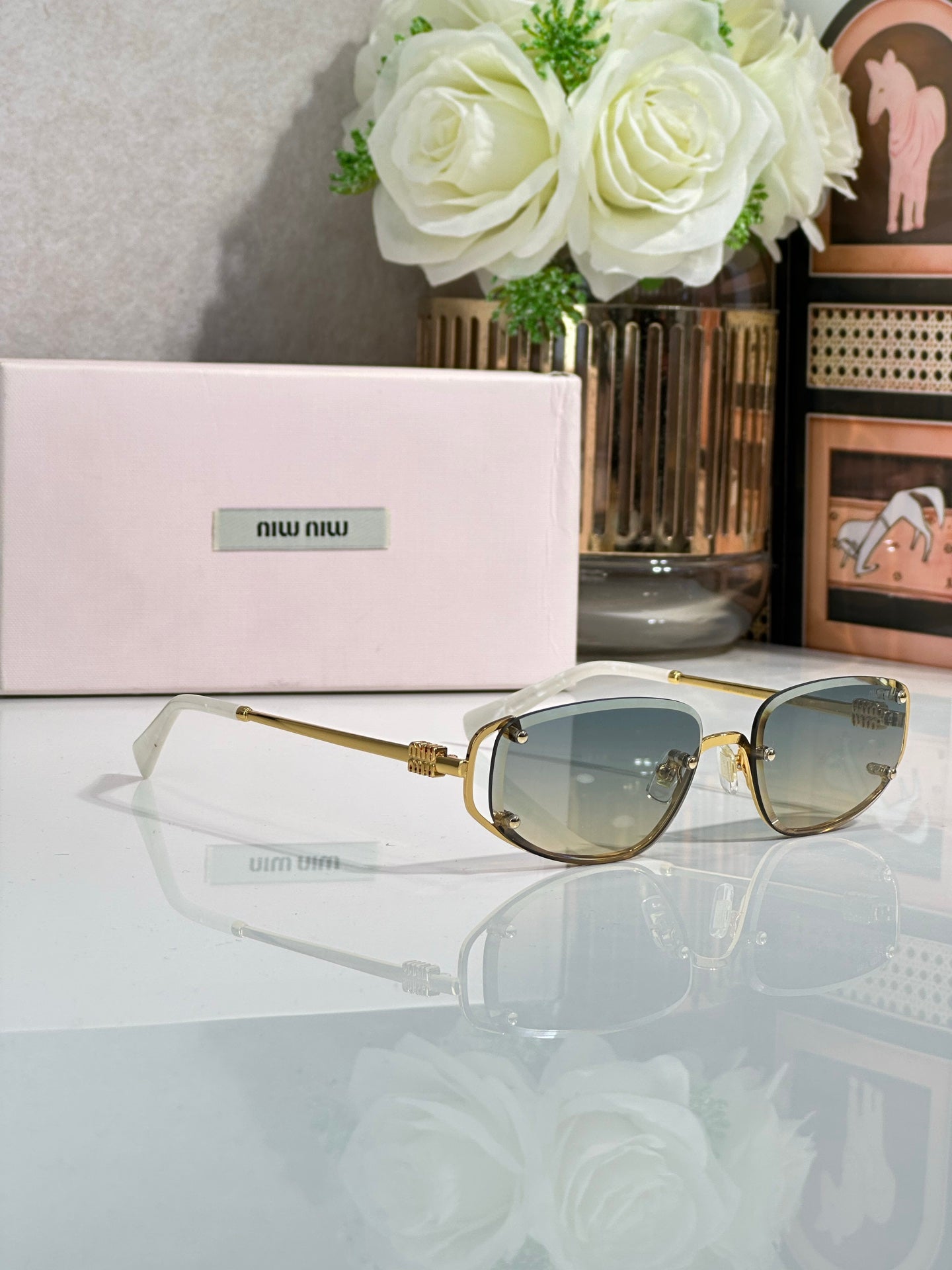 MiuMiu sunglasses with blue-tinted lenses and gold oval round frames