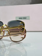 MiuMiu sunglasses close-up with gold frame and blue-tinted lenses
