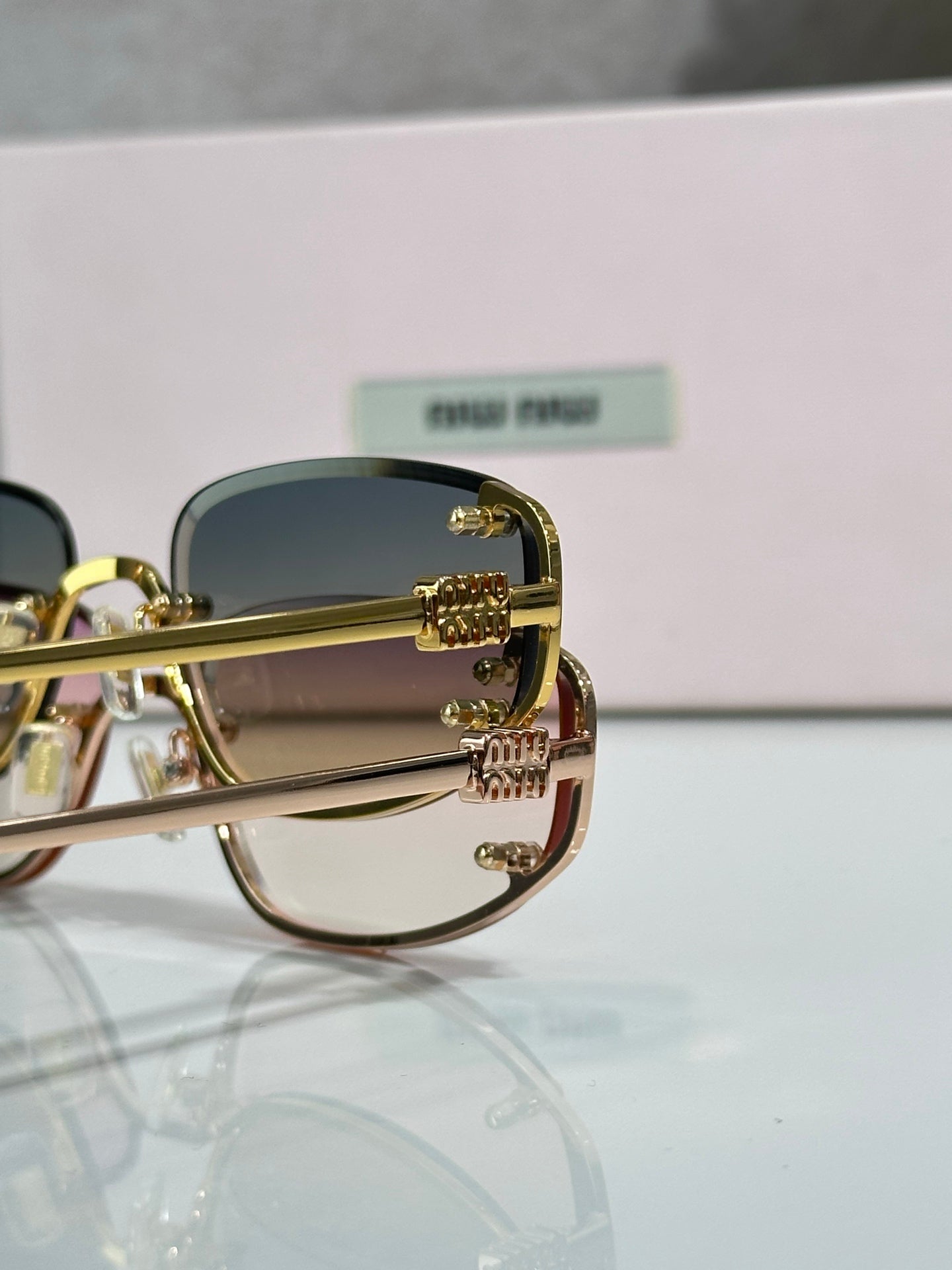 MiuMiu sunglasses close-up with gold frame and blue-tinted lenses