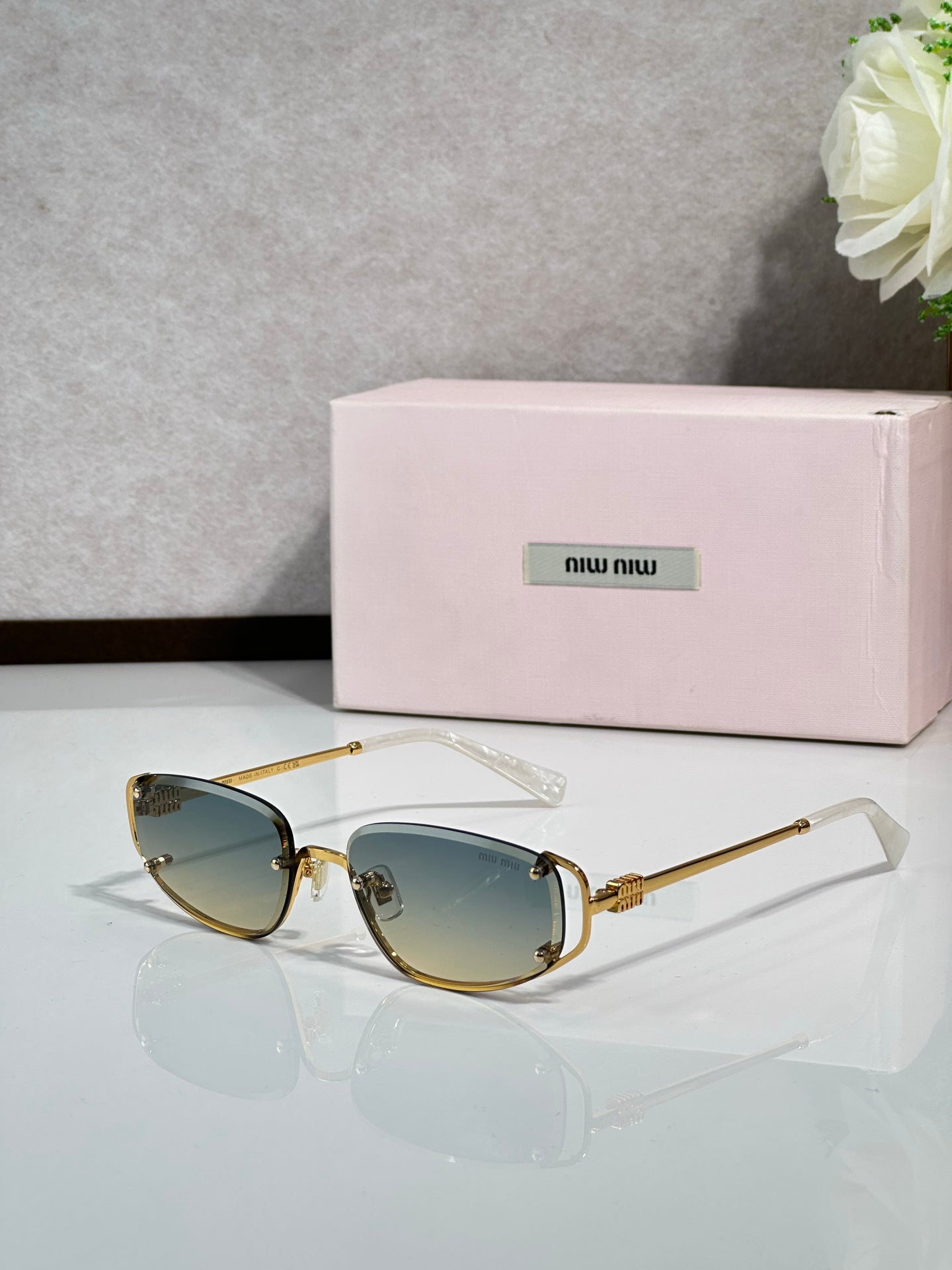 MiuMiu sunglasses with blue-tinted lenses and gold round frames