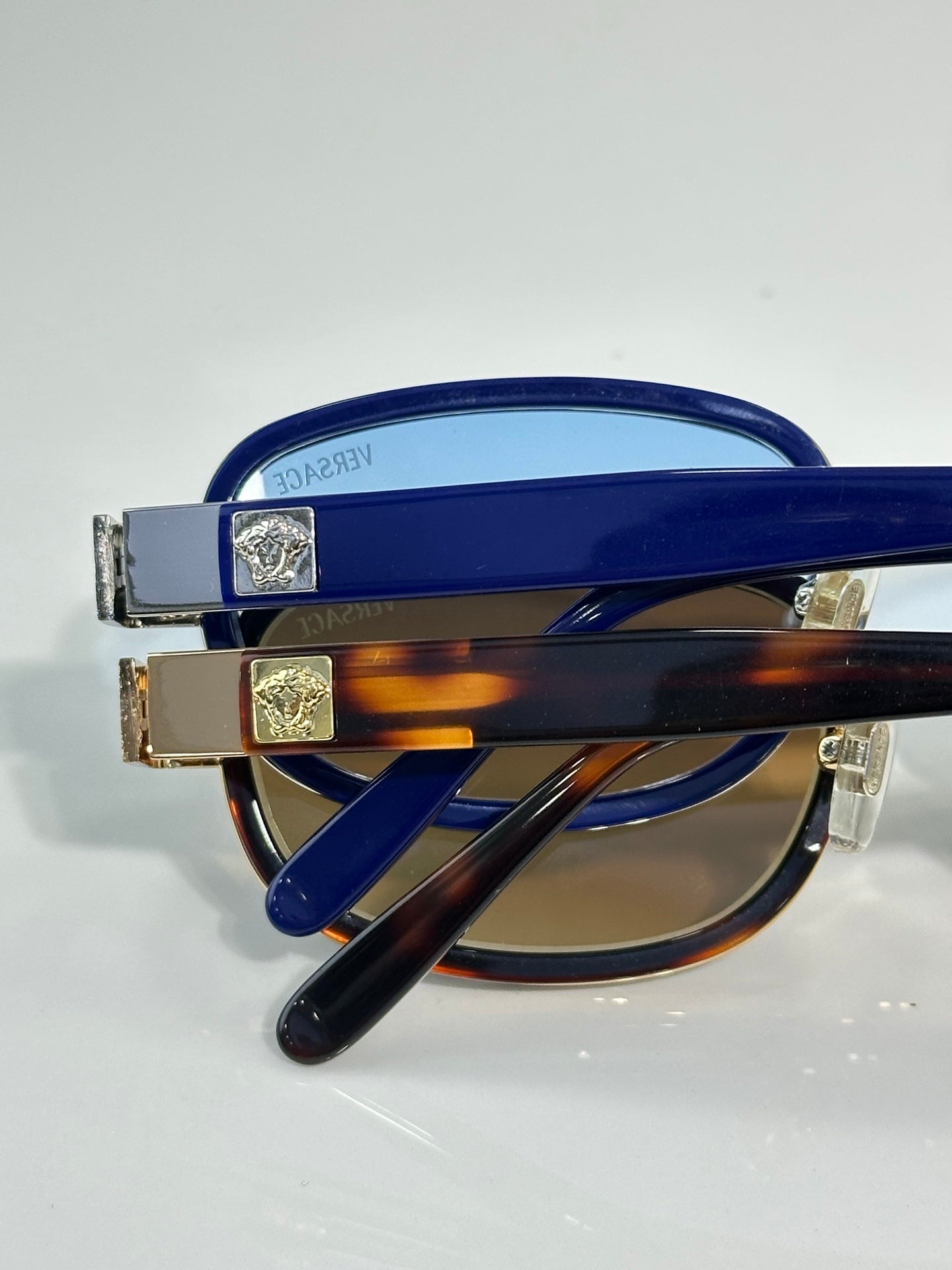 Versace sunglasses close-up with blue and tortoiseshell accents and gold hinges