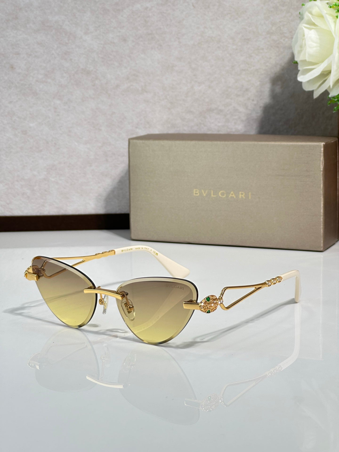 Gold-frame cat-eye sunglasses with pale yellow lenses and jeweled bridge