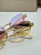 Close-up of gold sunglasses with pastel pink and yellow tinted lenses