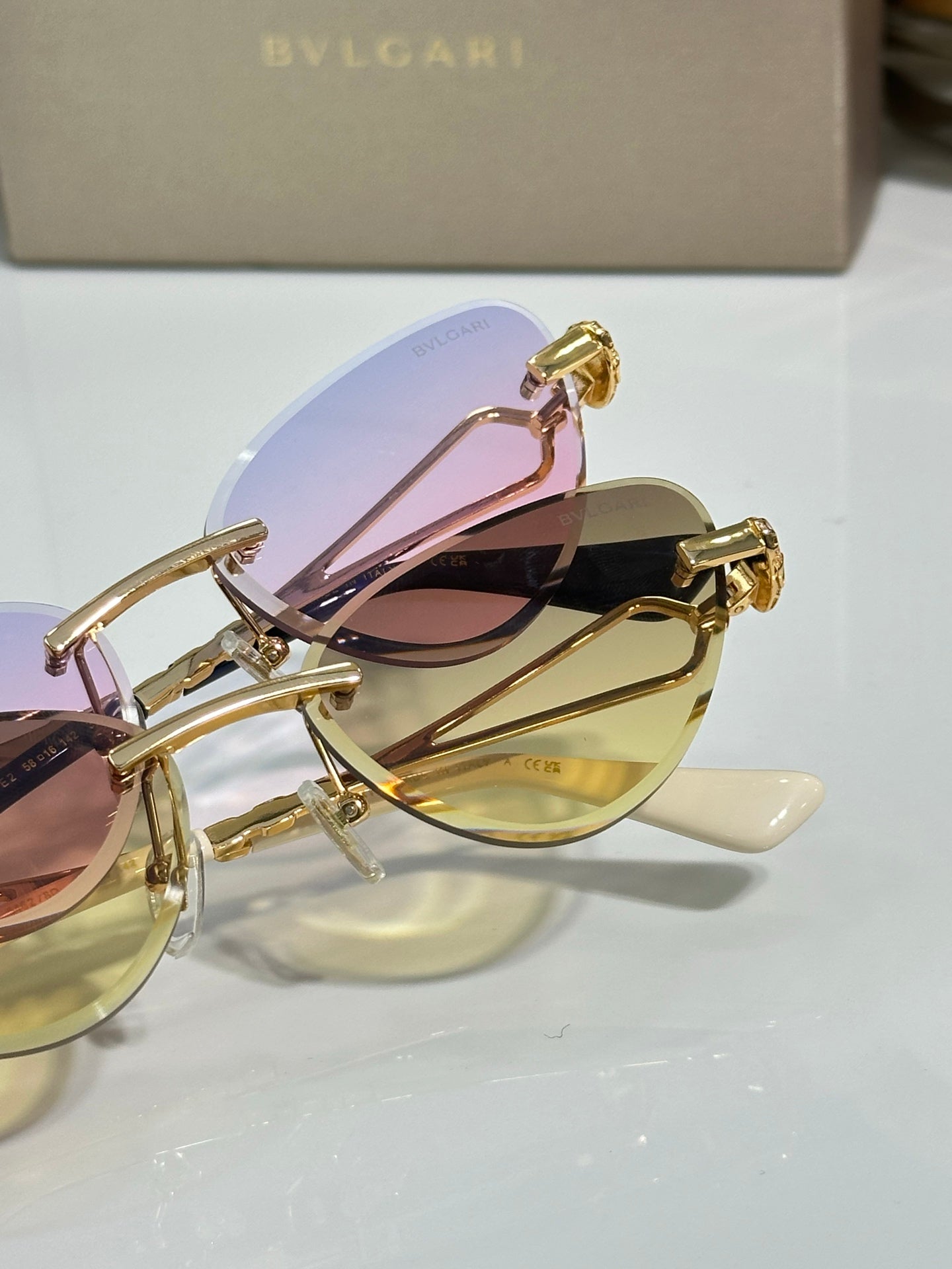 Close-up of gold sunglasses with pastel pink and yellow tinted lenses