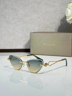 Gold-frame cat-eye sunglasses with teal lenses and jeweled center detail