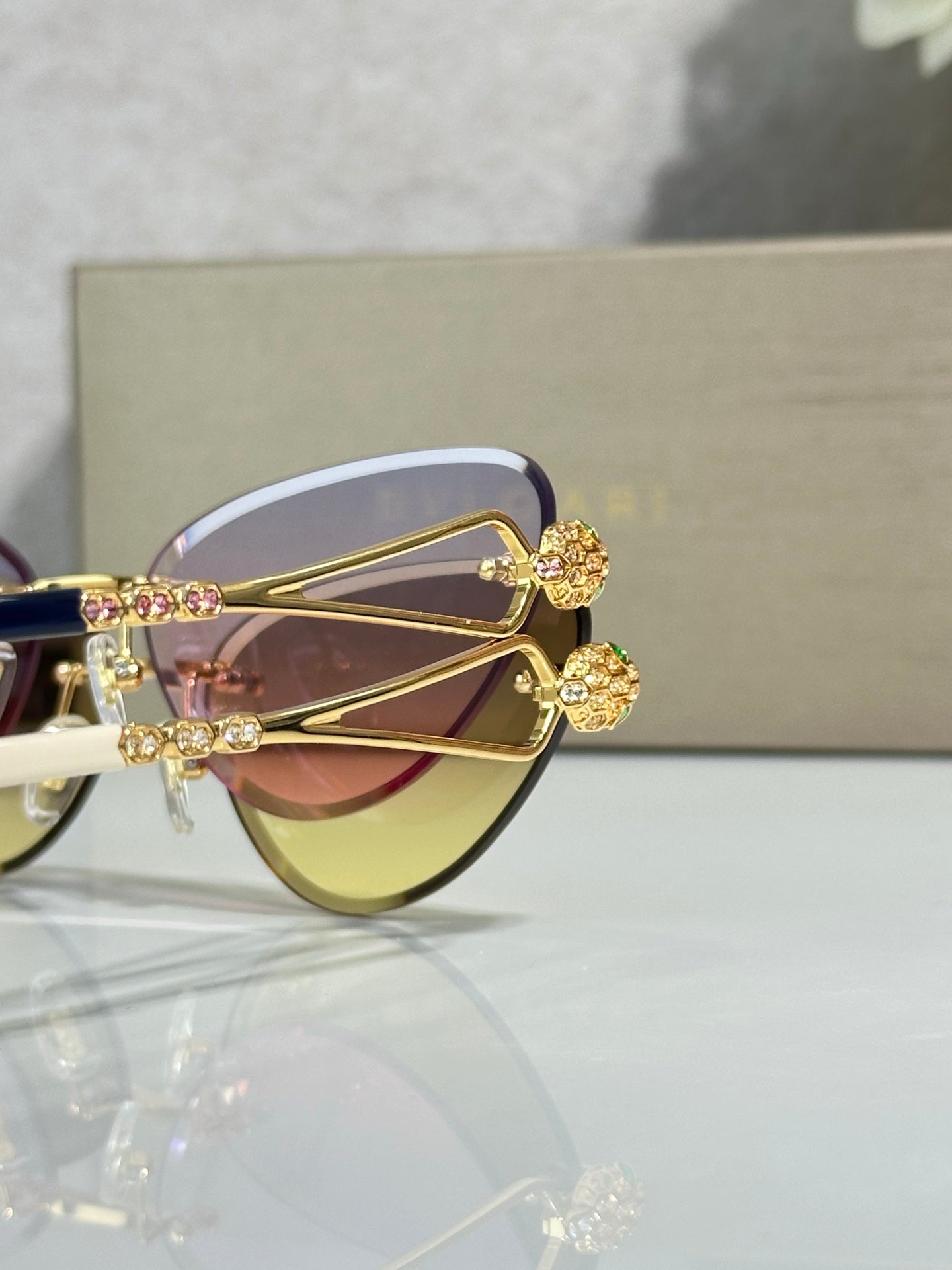 Close-up: gold sunglasses with flower-like jewel detailing and violet lenses