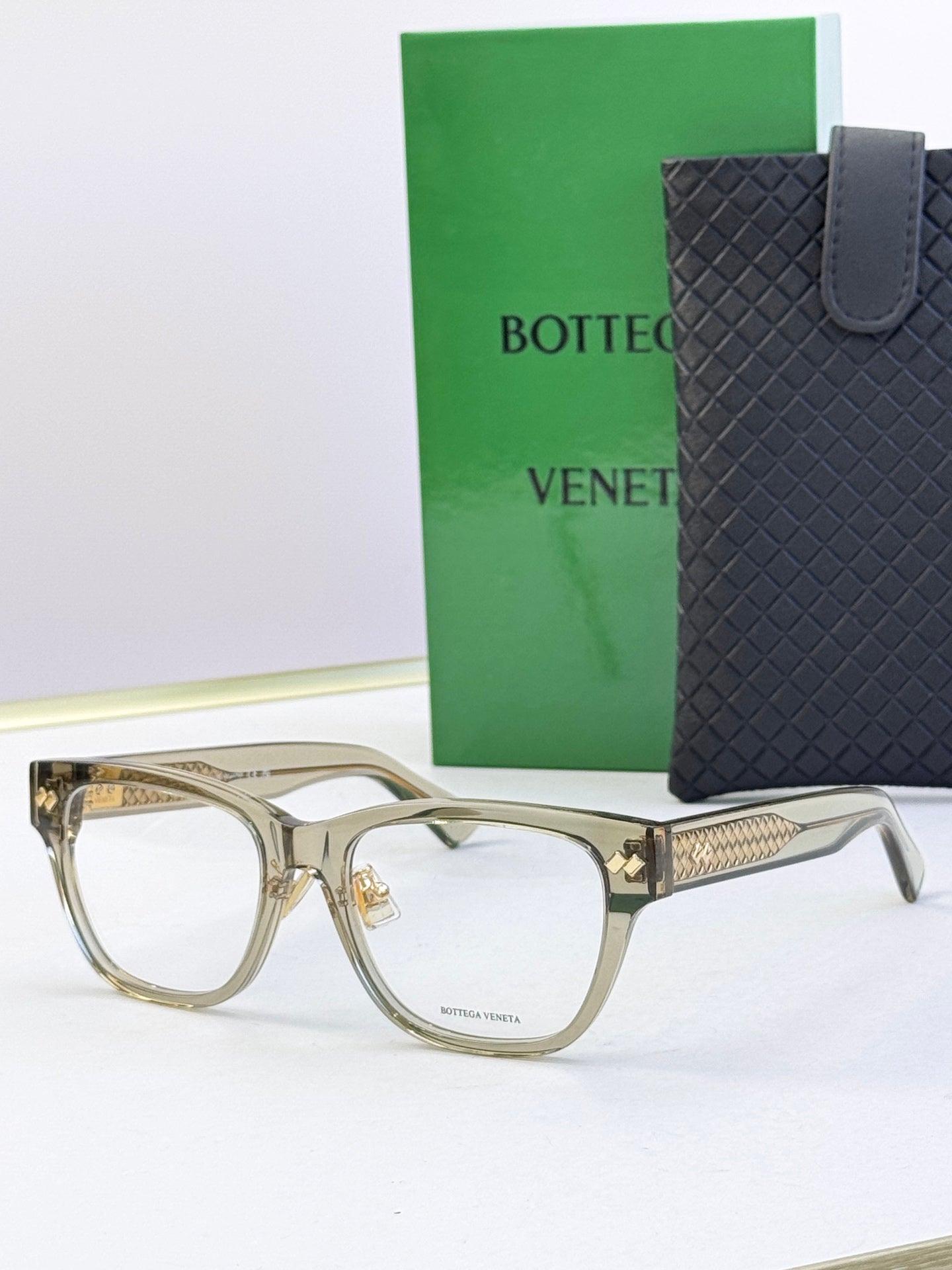Light gold eyeglasses with translucent frame and gold logo on temples.