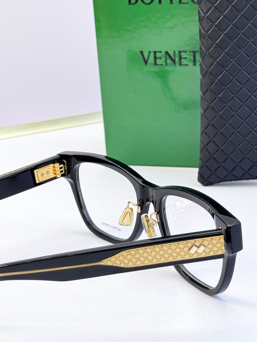 Black eyeglasses temple detail with gold inlay and metal hinge.