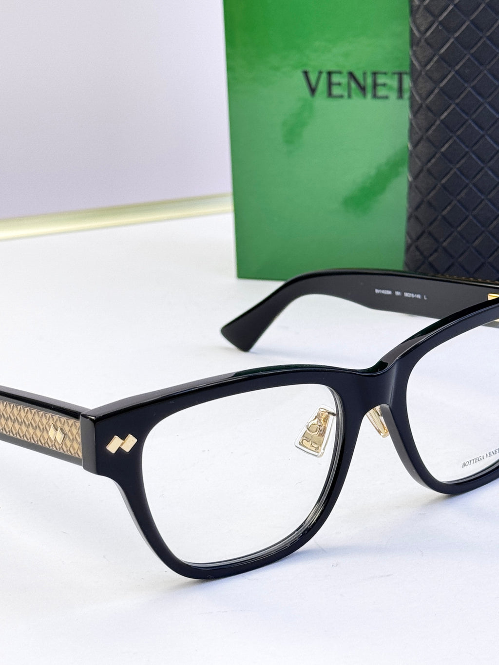 Black eyeglasses side view with gold-pattern temple detail.
