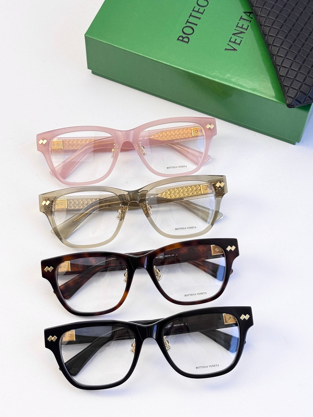 Assorted eyeglasses in pink, tortoise, and black with gold temple accents.